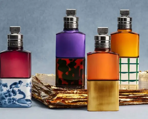 Vier bunte Parfumflaschen mit silbernen Verschlüssen auf goldenem Untergrund.