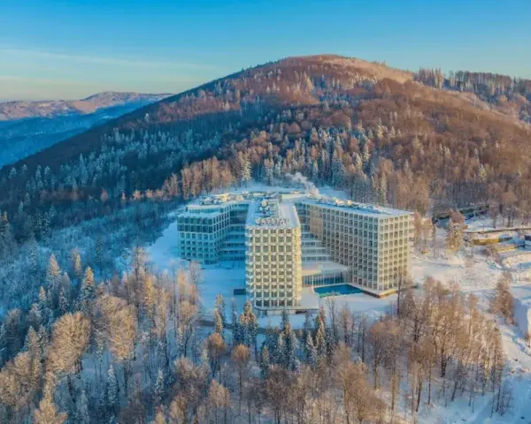 Nowoczesny hotel Crystal w zimowej scenerii, otoczony ośnieżonym lasem. To idealne miejsce na wypoczynek w Wiśle, górskim kurorcie.