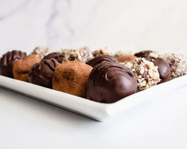 Variedad de trufas de chocolate, algunas cubiertas de cacao y otras con frutos secos picados. ¡Perfectas para aprender como hacer trufas de chocolate!