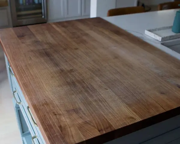 A close-up of a well-used butcher block countertop, showing the grain and minor scratches. This image illustrates how to clean butcher block countertops for a beautiful finish.