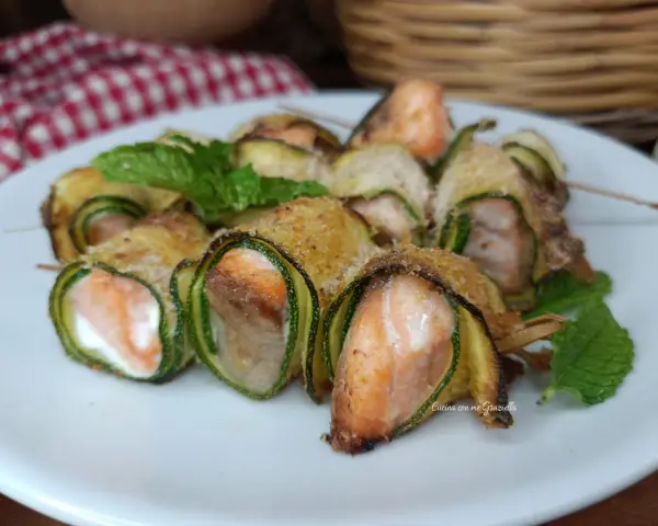 Deliziosi involtini di zucchine con salmone e formaggio, guarniti con menta fresca.