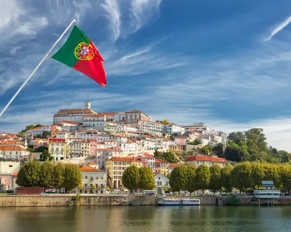 Wspaniała portugalia pogoda w grudniu. Flaga Portugalii powiewa nad malowniczym miastem na wzgórzu, z rzeką w tle.