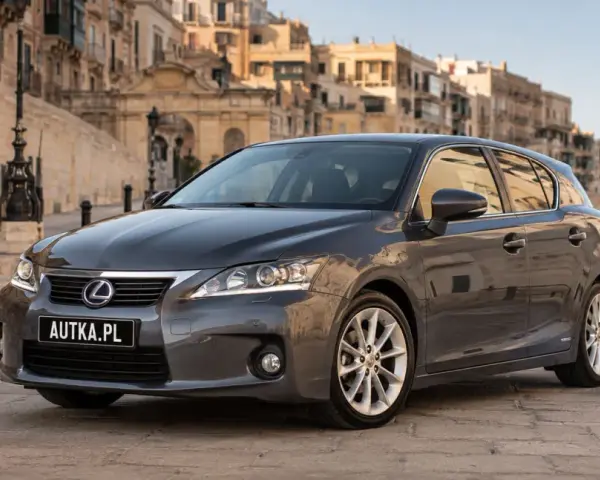 Szary Lexus CT 200h zaparkowany na brukowanej uliczce z zabytkowymi budynkami w tle.