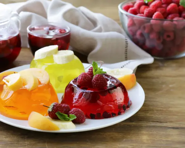 Tre colorate gelatine per dolci, guarnite con frutta fresca, invitano a un assaggio rinfrescante.