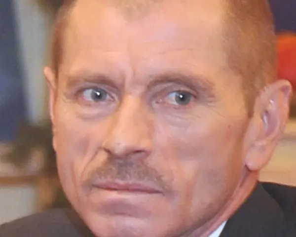 Portret Stanisława Pąka. Mężczyzna z wąsikiem patrzy w bok. W tle owoce.