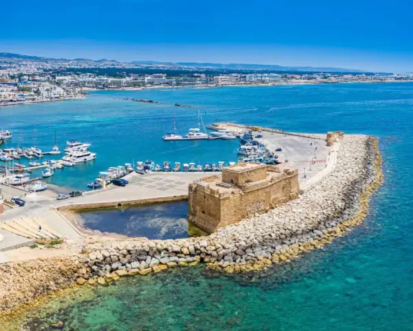 Pafos pogoda: Słoneczny dzień nad portem z zamkiem, jachtami i miastem w tle. Idealna pogoda na zwiedzanie Cypru.