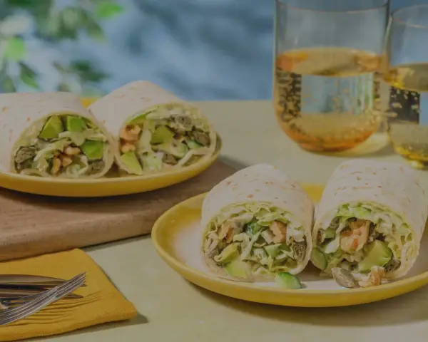 Leckeres Tortilla-Rezept mit Avocado und Garnelen, serviert auf gelben Tellern mit Gläsern mit Getränken.