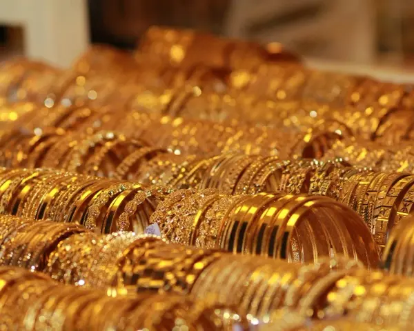Una ricca collezione di bracciali d'oro, molti con il marchio 750, brillano sotto la luce, creando un'abbagliante esposizione di lusso.