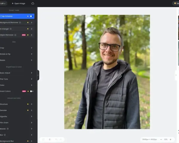 Mężczyzna w okularach uśmiecha się na tle parku. Interfejs programu Fotor oferuje darmowy program do obróbki zdjęć po polsku.