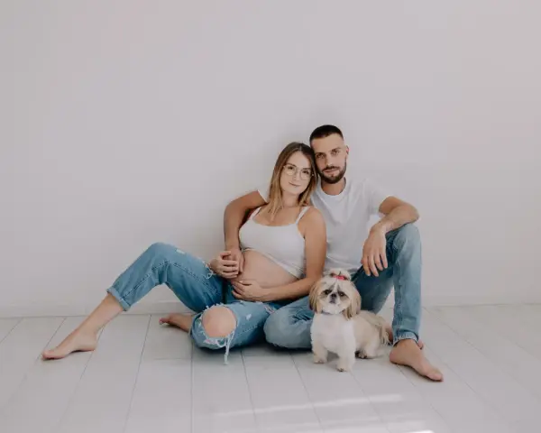 Ciąża w obiektywie laura kania fotografia: przyszli rodzice z pieskiem siedzą na podłodze.