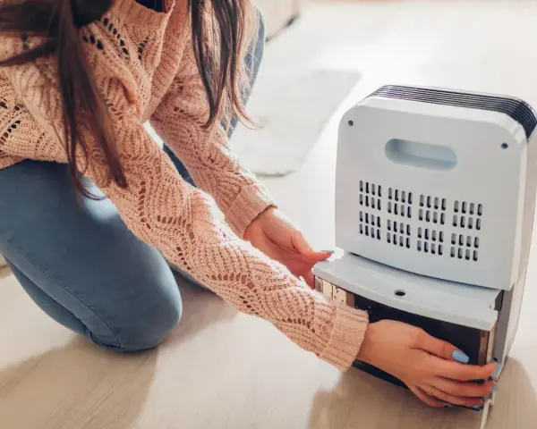 Donna controlla il serbatoio del deumidificatore, sperando che non faccia acqua.