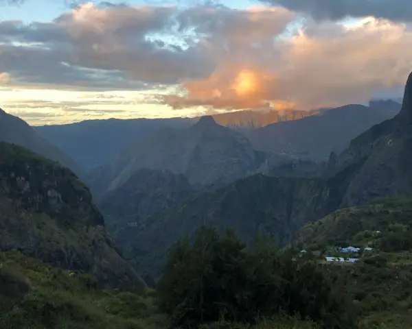 Al tramonto, le montagne della "diagonale des fous" si tingono di rosa. Un villaggio si intravede tra le valli verdi.