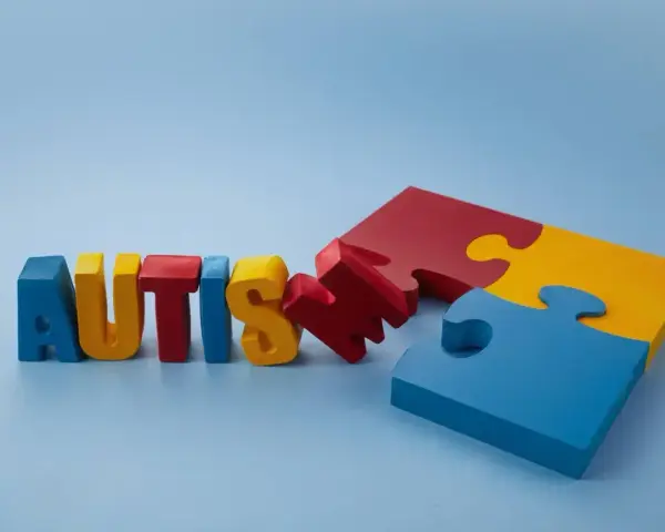 Kolorowe litery układają się w napis "AUTISM", obok fragmenty puzzli. Szukamy leków na autyzm dla dzieci, by pomóc im w rozwoju.