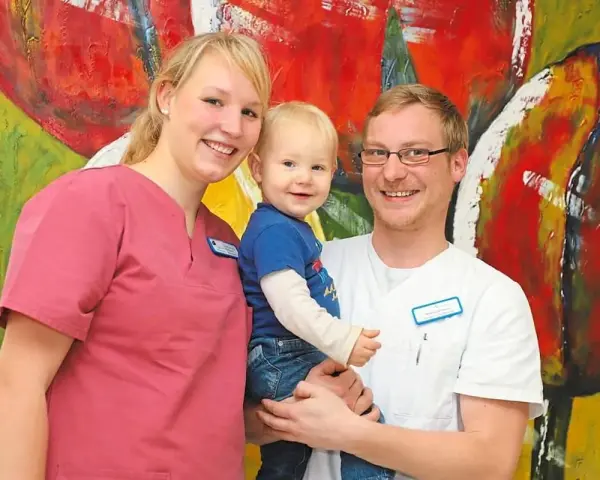 Glückliche Familie vor bunter Kunst. Das Bild thematisiert das Arbeitsrecht bei Schichtarbeit mit Kind.