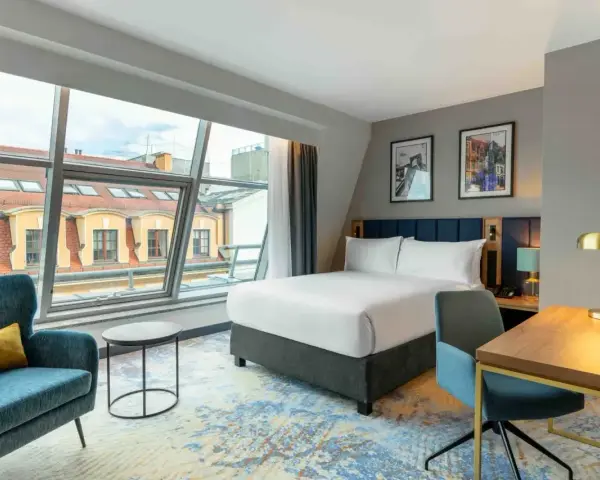 Nowoczesny pokój hotelowy z dużym oknem, łóżkiem i biurkiem. Czy trzeba być pełnoletnim, aby wynająć hotel? Tak, zazwyczaj tak.