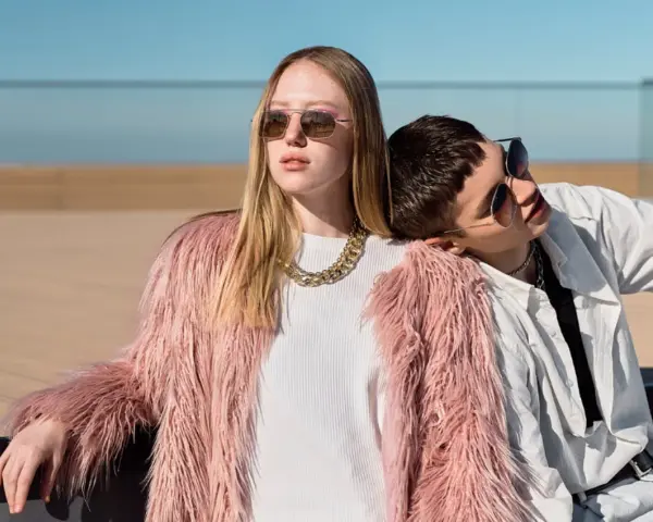Chica con abrigo rosa peludo y collar dorado, apoyada en un chico con camisa blanca. Inspiración para como ser una chica aesthetic.