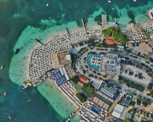 Albania najpiękniejsze miejsca: tętniący życiem kurort plażowy z białymi parasolami, turkusową wodą i basenami.