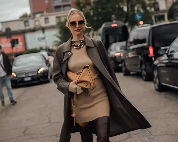 Une femme élégante porte un trench-coat kaki sur une robe moulante beige, un sac Fendi et des bottes hautes. Parfait pour savoir quoi mettre par-dessus une robe de soirée.
