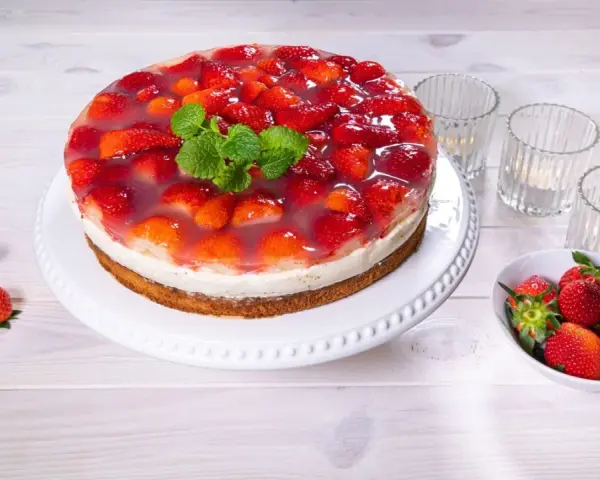 Eine köstliche Erdbeer Joghurt Sahne Torte, bedeckt mit frischen Erdbeeren und Tortenguss, garniert mit Minze.