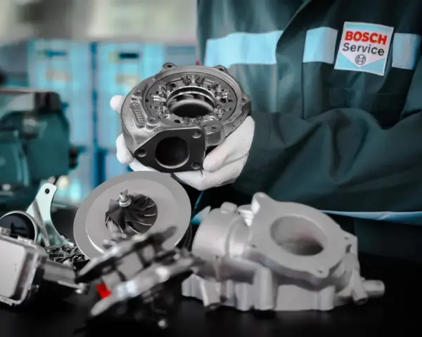Mechanik w rękawiczkach prezentuje turbosprężarkę, być może powiązaną z błędem dtc p1693 volkswagen.