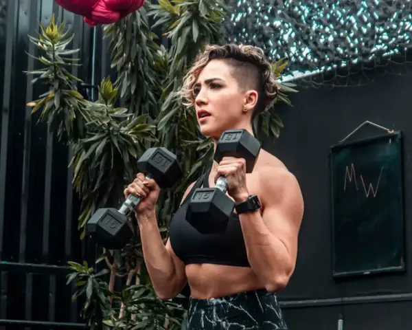Kvinna utför hammer curls med hantlar. Stark och fokuserad, redo för nästa repetition.