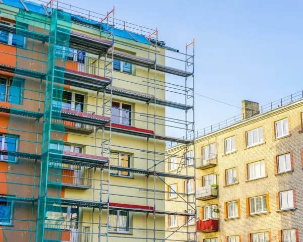 Budynek w remoncie, rusztowania i siatka ochronna. Balkony we wspólnocie mieszkaniowej czekają na odnowienie.