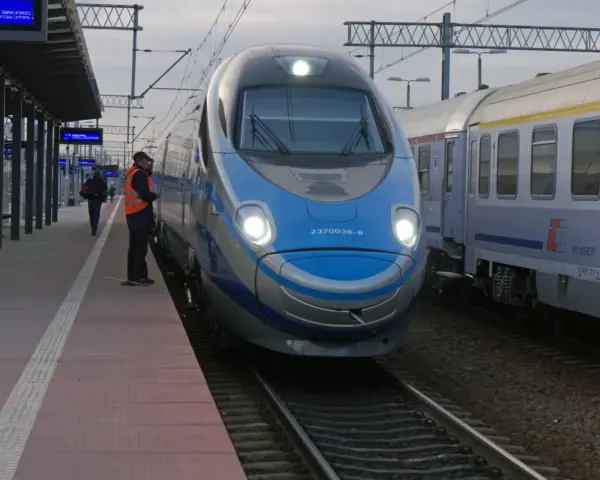 Pendolino Warszawa-Kraków na peronie. Maszynista w kamizelce odblaskowej czeka na pasażerów.