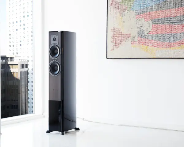 Elegancki głośnik Dynaudio Contour 30 w nowoczesnym wnętrzu, obok okna z widokiem na miasto.