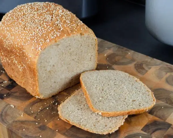 Frisch gebackenes sesam brot, mit zwei Scheiben auf einem Holzbrett.