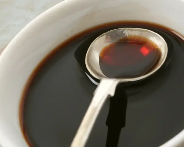 Łyżka z ciemnym płynem, idealnym do sosów i dressingów. Inspiracja do ocet balsamiczny przepisy.