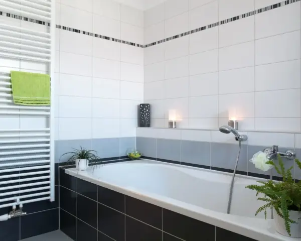Salle de bain moderne avec baignoire, radiateur blanc et carrelage impeccable. Les joints de carrelage sont parfaits, donnant une finition propre.