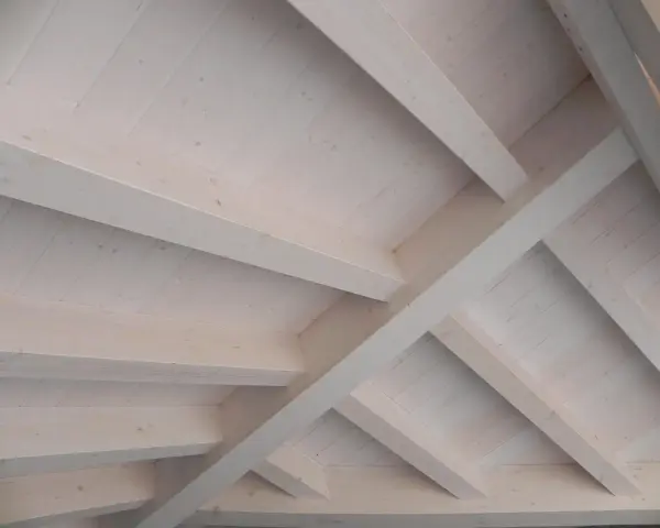 Techo de madera con vigas y tablones, acabado con veladura blanca que resalta la veta natural.