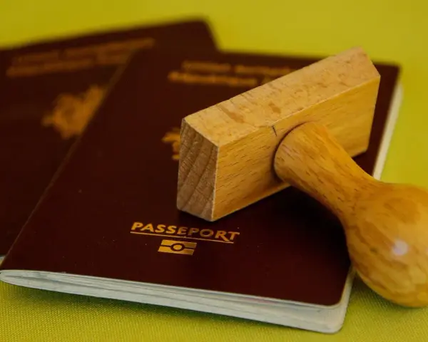Drewniany stempel nad paszportem, gotowy do pieczętowania. Marzysz o podróży? Biuro paszportowe Lublin pomoże Ci spełnić marzenia.