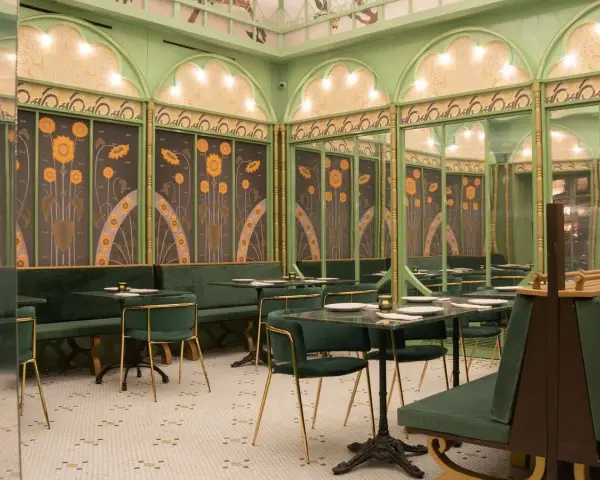 Elegante restaurante con mesas y sillas verdes, paredes decoradas con girasoles y detalles dorados. Un lugar perfecto para disfrutar de **frases restaurante** inspiradoras.