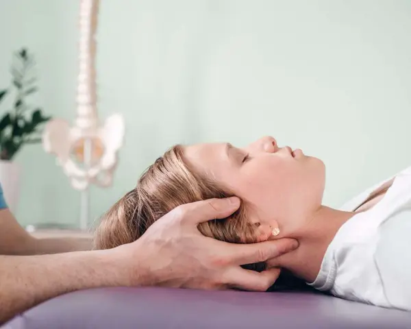 Delikatna terapia krzyżowo czaszkowa dla ulgi w napięciu. Terapeuta delikatnie uciska głowę pacjentki.