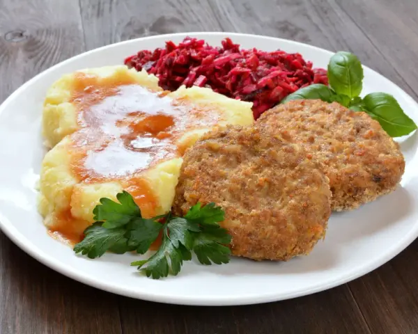 Dwa soczyste mielone z piekarnika, podane z purée ziemniaczanym polanym sosem, surówką z buraków i listkami bazylii.