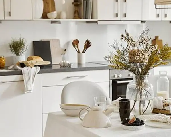 Cuisine lumineuse dans une maison style cottage anglais, avec vaisselle et bouquet de fleurs séchées sur la table.