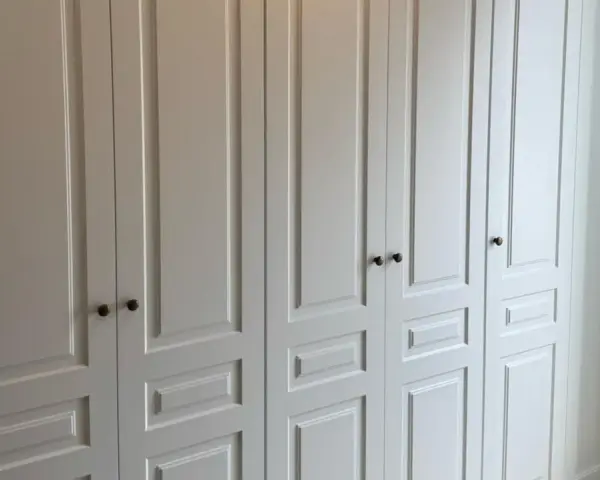 Armario empotrado blanco con puertas de paneles y tiradores oscuros. Perfecto para forrar armario empotrado y dar un toque elegante.
