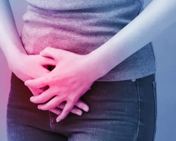 Osoba trzyma się za brzuch, odczuwając ból. Może to być objaw problemów, w leczeniu których pomaga Ditropan.