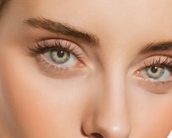 Maquillage subtil pour paupières tombantes, rehaussé par le regard intense derrière des lunettes imaginaires.