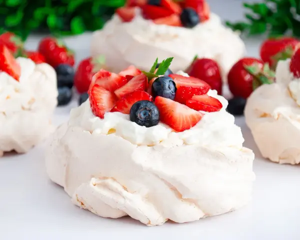 Klasyczna Pavlova z owocami i kremem lub małe beziki z kremem. Pyszne, lekkie desery.