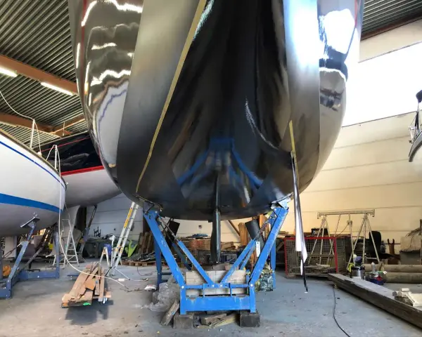 Schwarzer Rumpf einer Yacht im Trockendock, bereit, das Antifouling zu erneuern.
