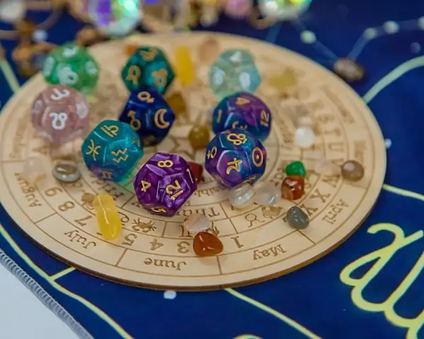 Kości z symbolami zodiaku i numerami 5 i 9, kamienie i talizmany na tle zodiakalnym.