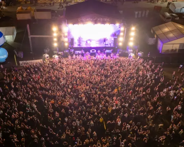 Tłum ludzi na koncercie podczas Cieszynów Rock Festiwal. Na scenie gra zespół, a przed nią tysiące fanów.