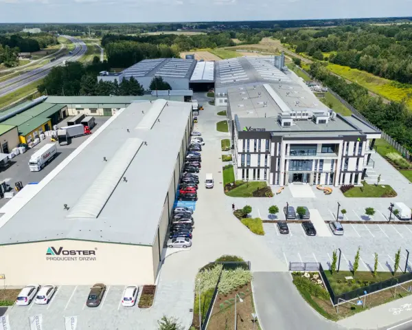 Nowoczesny kompleks produkcyjny Voster producent drzwi, z drogą szybkiego ruchu w tle.