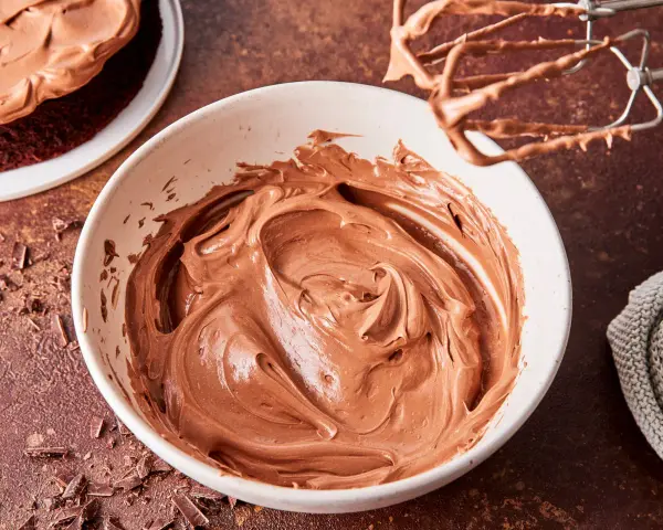 Schokocreme mit Puddingpulver, cremig und glatt, bereit für einen köstlichen Kuchen. Ein Handmixer mit Schokoladenresten liegt daneben.