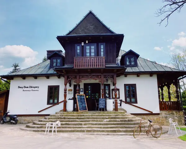 Stary Dom Zdrojowy w Beskidach, z charakterystyczną architekturą i kamiennymi schodami, zaprasza do restauracji.