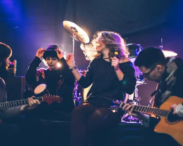 Band bei der Probe, die eine **cover musik** spielt. Sängerin mit Mikrofon, Gitarristen und Schlagzeuger im Scheinwerferlicht.