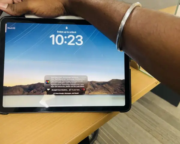 Tablet z włączonym ekranem blokady, widoczny napis "Touch ID" i godzina 10:23. Na ekranie wyświetla się powiadomienie z kodem weryfikacyjnym.