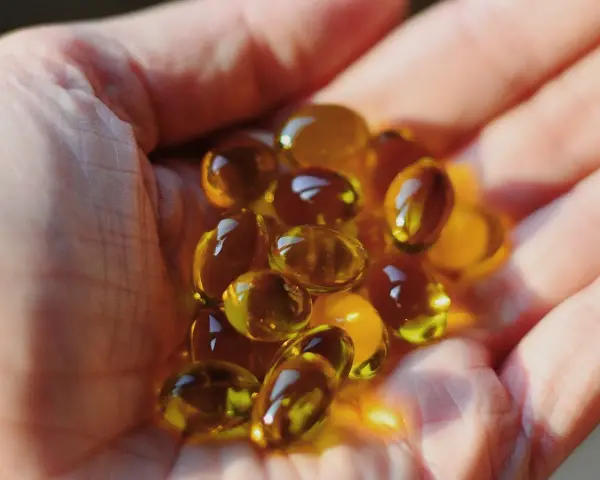 Une main tient des capsules d'huile de bourrache et onagre, un soutien naturel pour la ménopause.